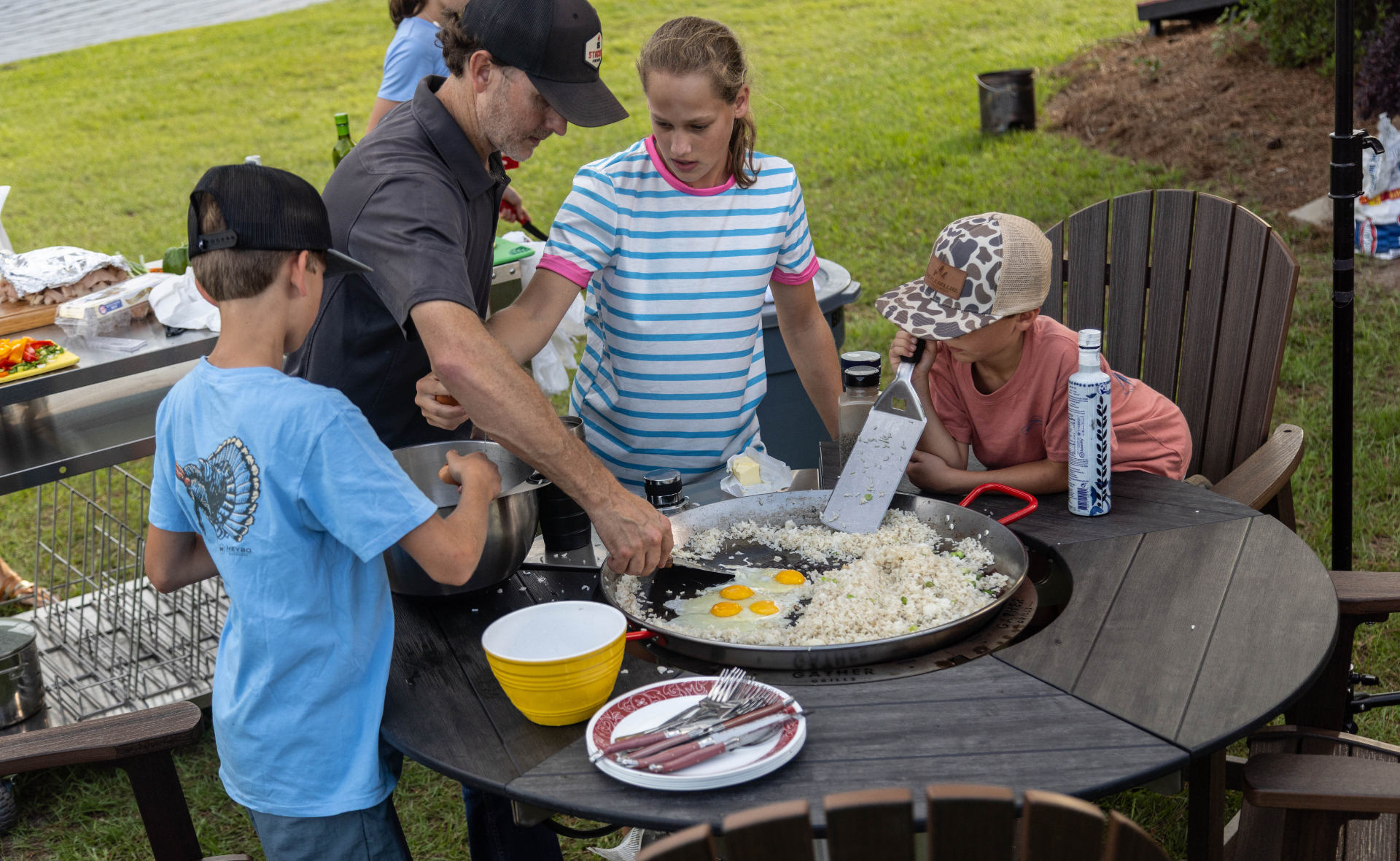 Family cooking rice and eggs together on an outdoor multi-functional grill and griddle.