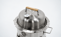 Stainless steel charcoal grill with thermometer and wood handle lid on white background